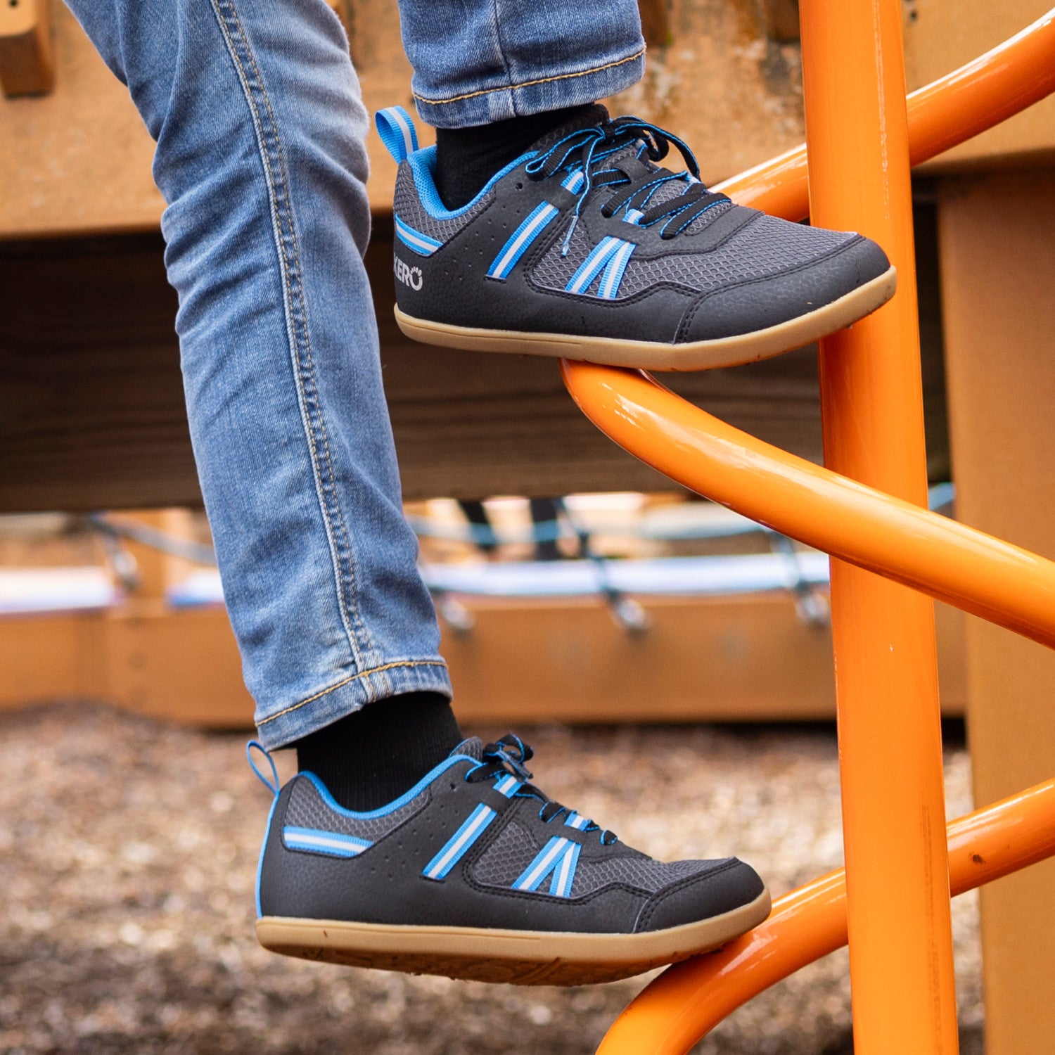 Die Xero Shoes Prio Youth in Schwarz und Blau als komfortable Barfußschuhe für Kinder, am Fuß gezeigt, erhältlich in unserem Onlineshop für Barfußschuhe.