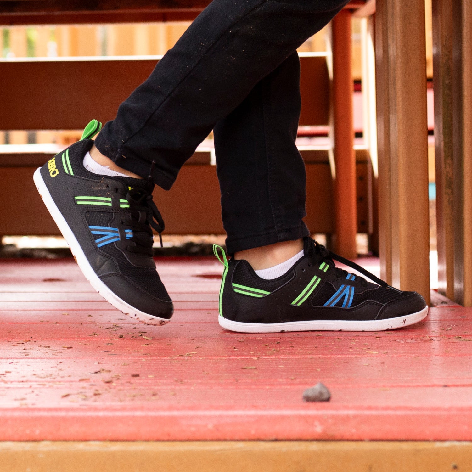 Die Xero Shoes Prio Youth in Schwarz und Lime als komfortable Barfußschuhe für Kinder, am Fuß gezeigt, erhältlich in unserem Onlineshop für Barfußschuhe.