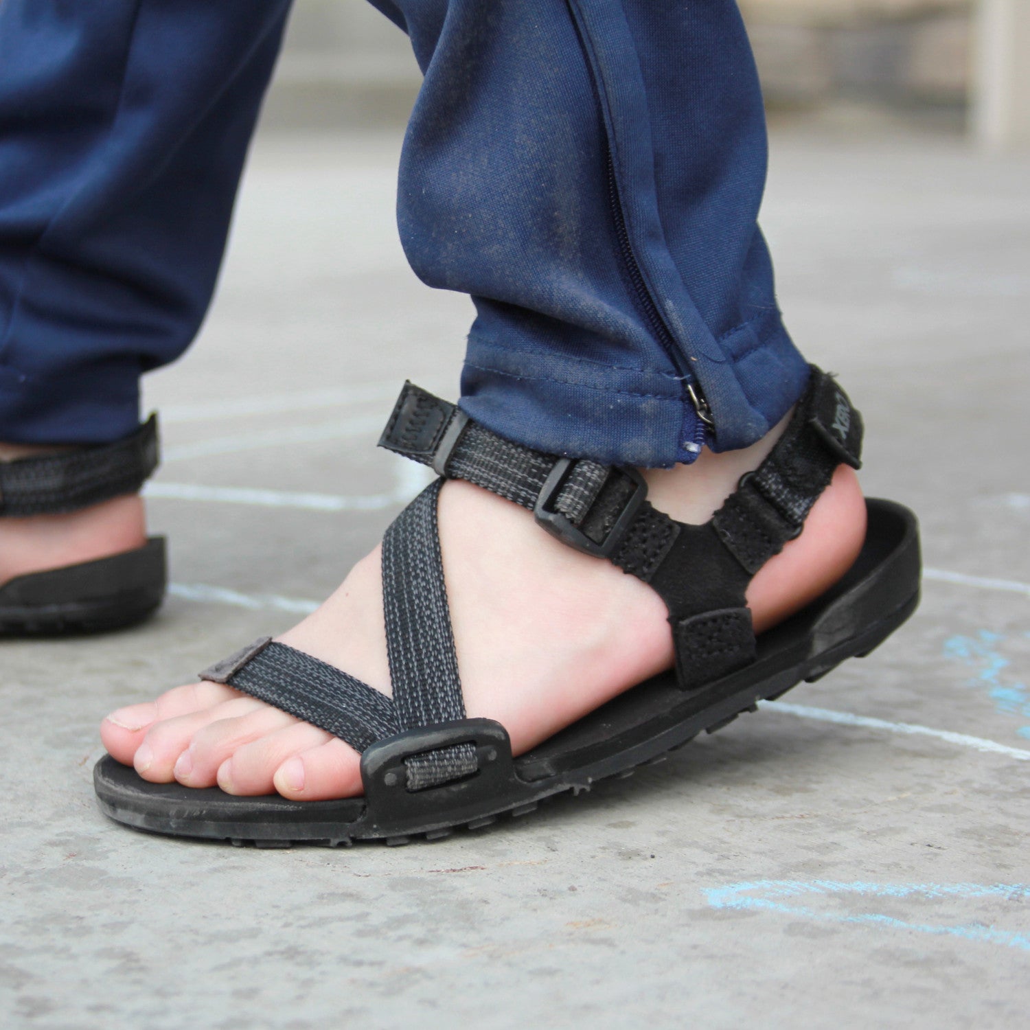 Xero Shoes Z-Trail Kids schwarze Barfuß-Sandalen für Kinder – am Fuß eines Kindes präsentiert, verfügbar im barfusswelten.de Barfußschuhe Onlineshop