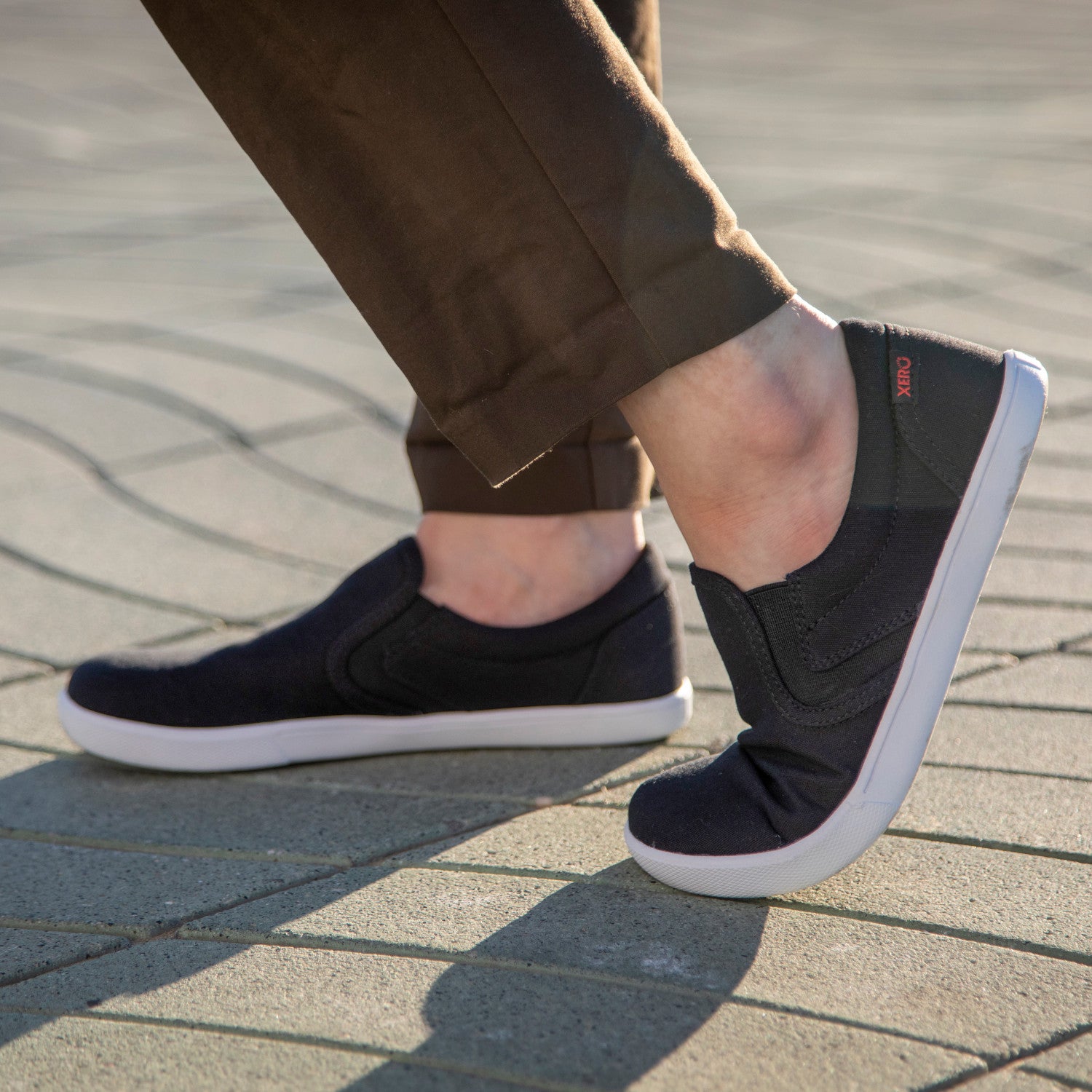 Xero Shoes Dillon Canvas Slip-On Barfußschuhe für Herren in Schwarz, gezeigt im Alltagseinsatz, bequem und ideal für jede Gelegenheit. Erhältlich in unserem Onlineshop für Barfußschuhe.