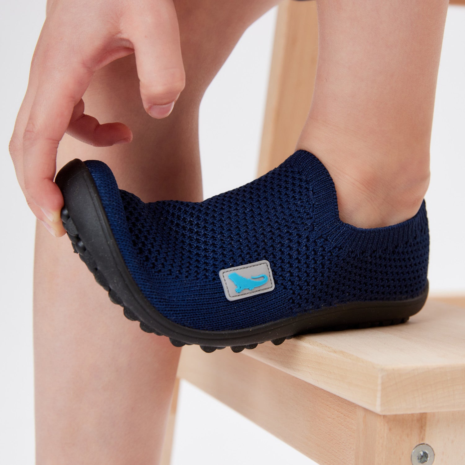 Leguanito Scio Leguano Kinder Barfußschuhe Slipper in Blau (Größen 29 bis 34) – im Alltag getragen von einem Kind, das spielerisch in einer Wiese unterwegs ist. Erhältlich im Barfußschuhe Onlineshop Barfusswelten.de.