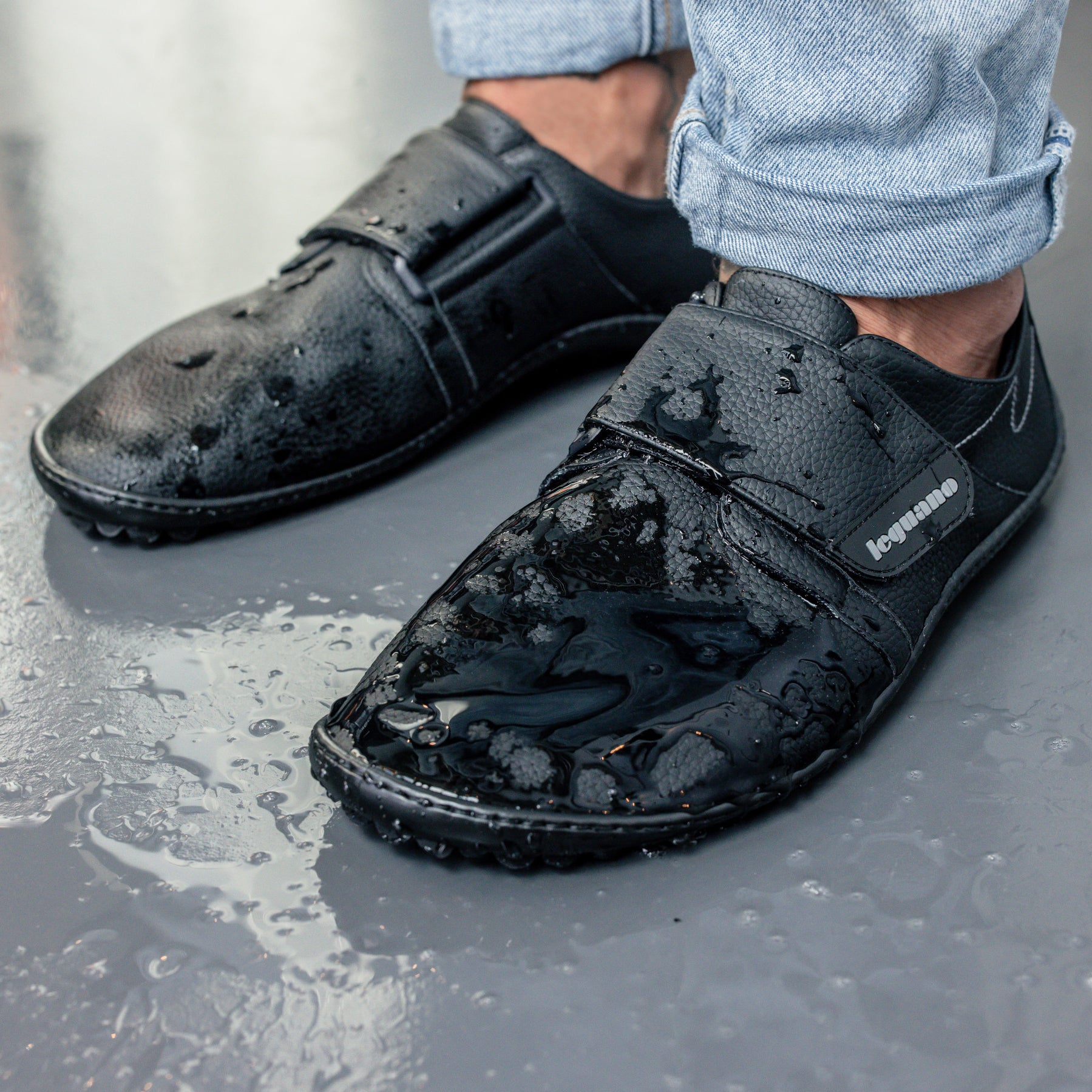 Schwarze Leguano Neron Barfußschuhe, wasserabweisende Sneaker in Aktion mit Wasser, ideal für Alltag und Outdoor, im Onlineshop für Barfußschuhe erhältlich.