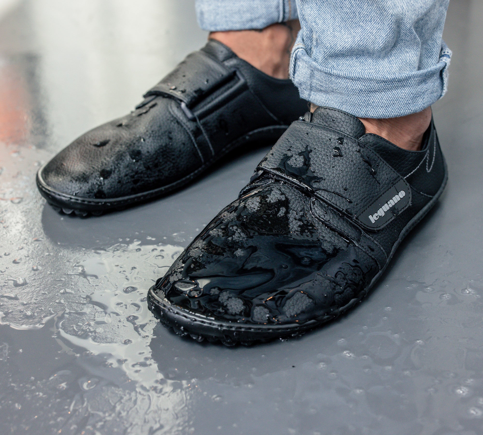 Schwarze Leguano Neron Barfußschuhe, wasserabweisende Sneaker in Aktion mit Wasser, ideal für Alltag und Outdoor, im Onlineshop für Barfußschuhe erhältlich.
