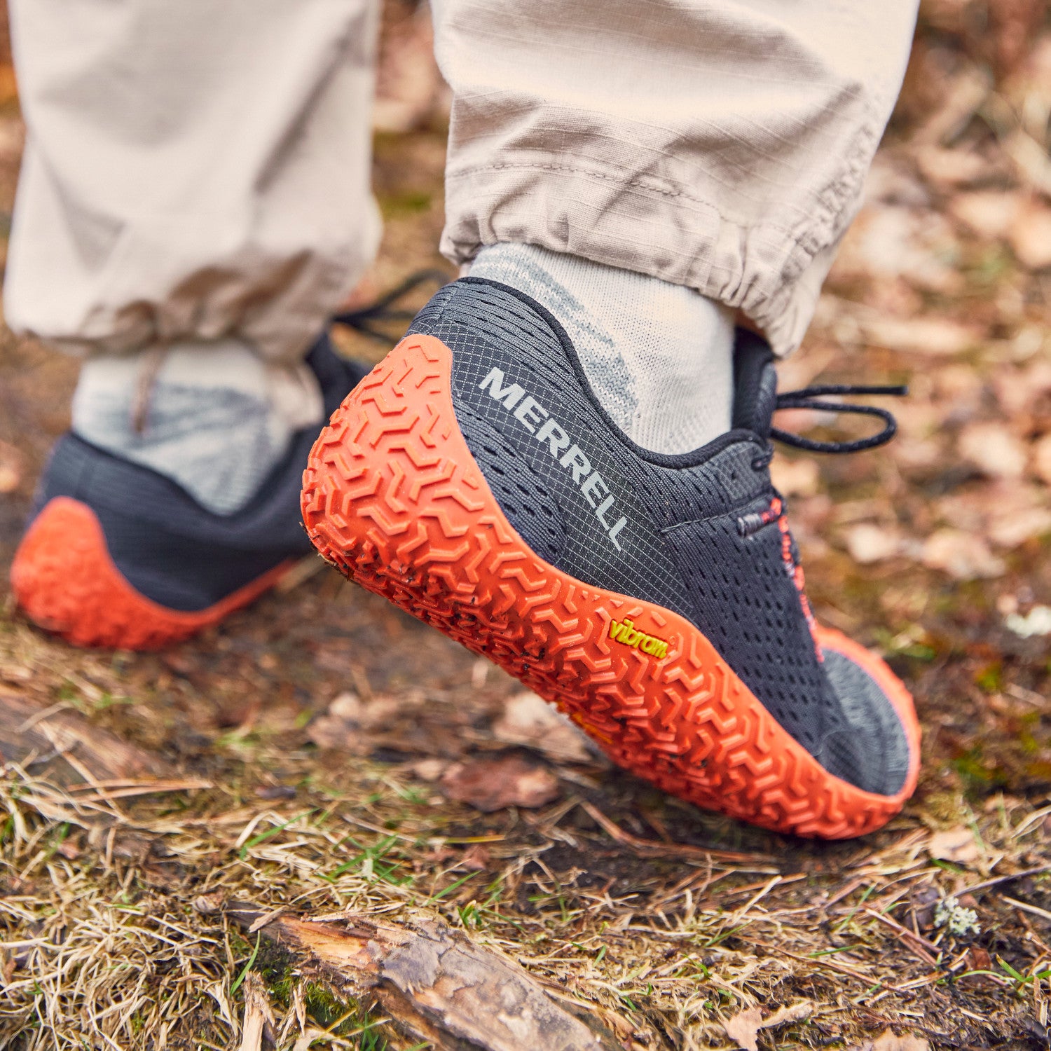 Merrell Vapor Glove 6 Barfußschuhe für Herren in Granite und Tangerine, gezeigt beim Tragen, verfügbar in unserem Onlineshop für Barfußschuhe